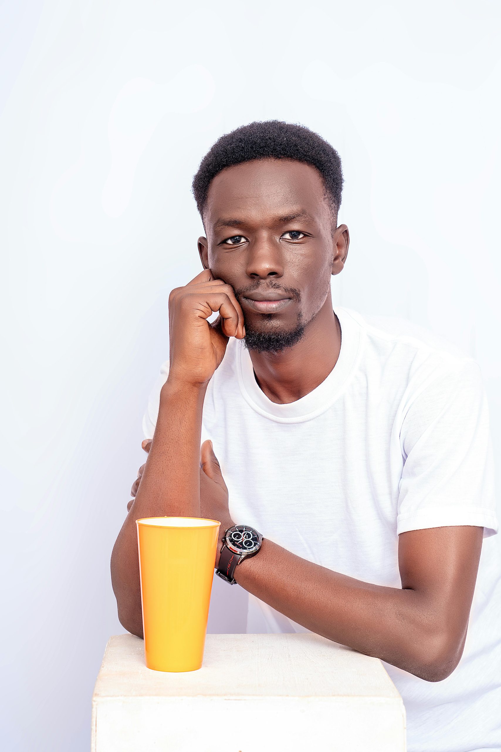 Portrait of a thoughtful man in white tee with orange cup. Minimalist style.